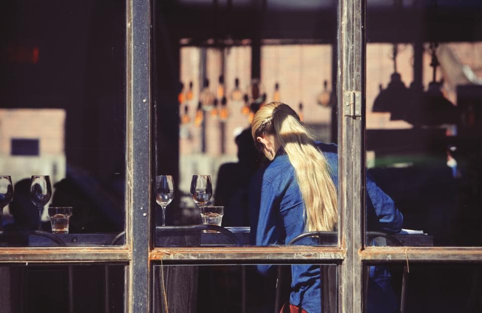 Une serveuse dresse une table près de la baie vitrée d’une salle.